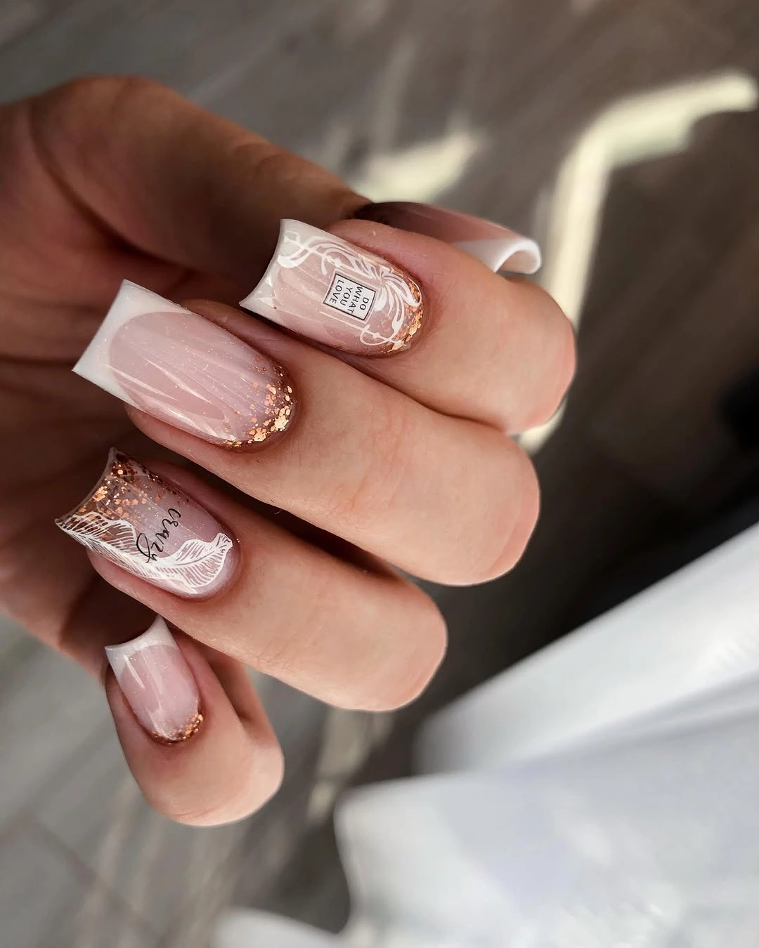 Rose gold French nails with ornate white motifs
