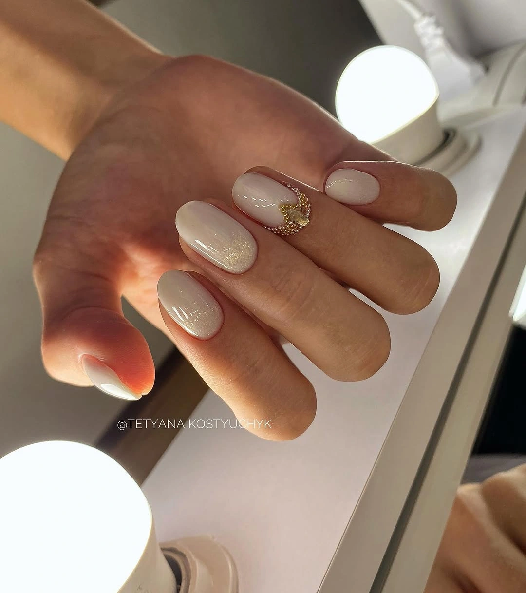Short oval milky nails with gold accent curve