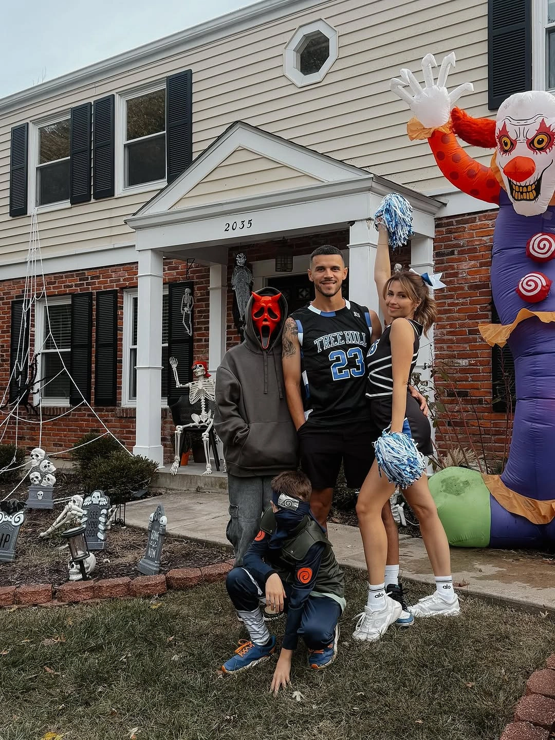 Family in dark streetwear costumes with masks and Halloween decorations