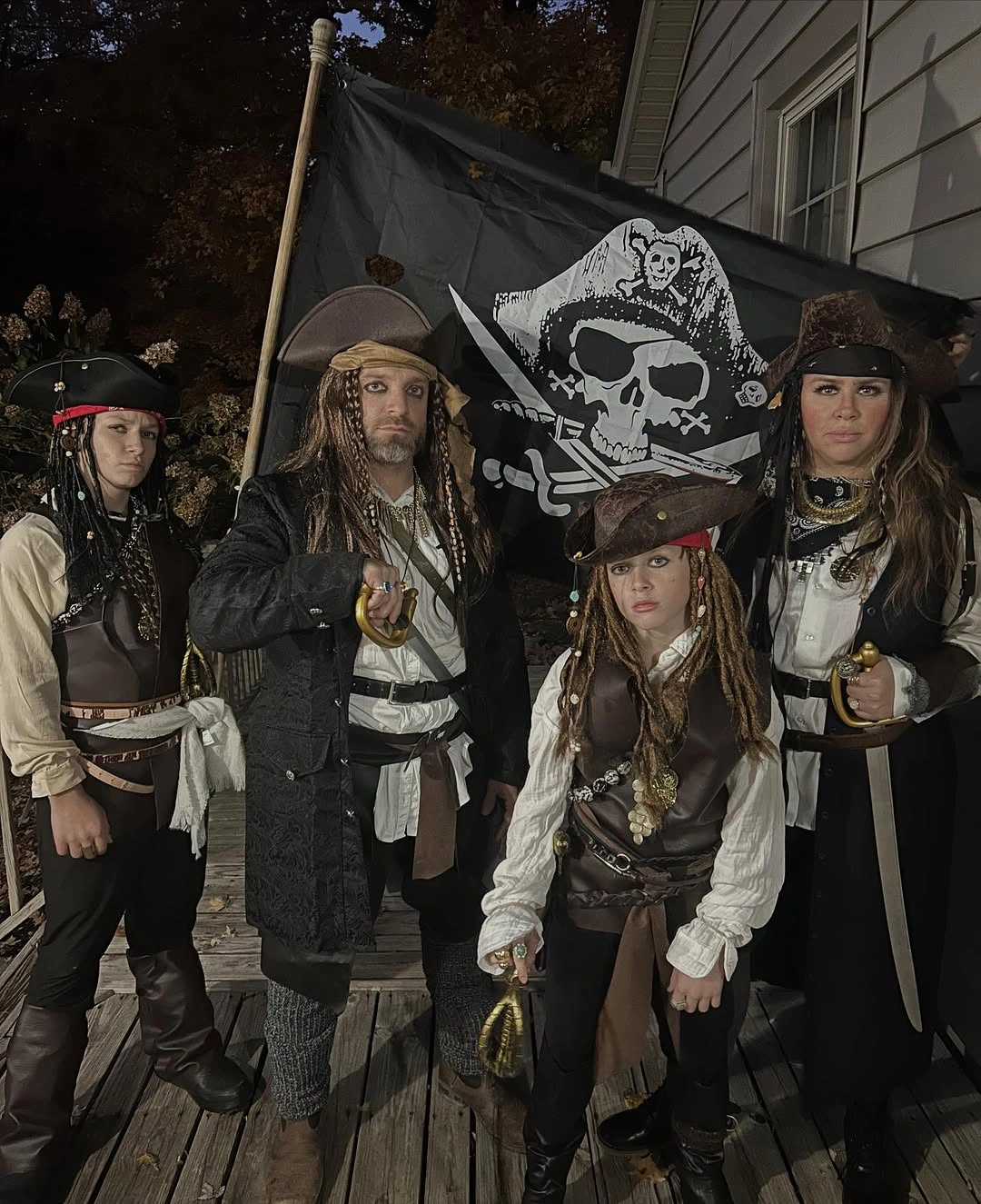 Family in layered pirate costumes with black skull flag