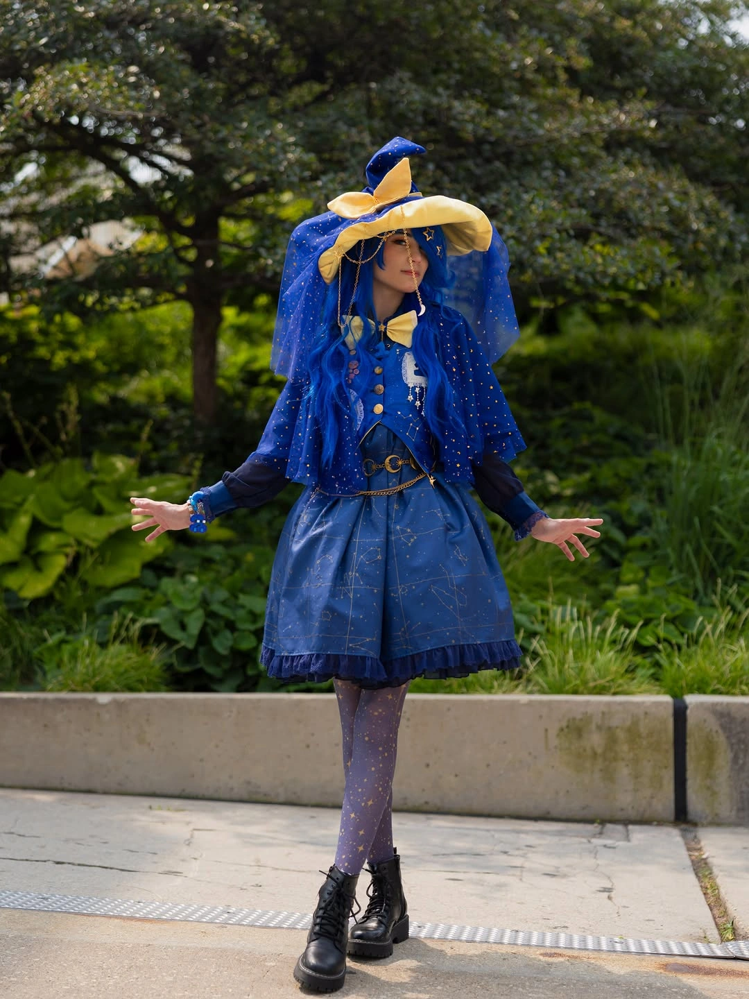 Girl in blue witch cape gold trim pointed hat purple tights and boots