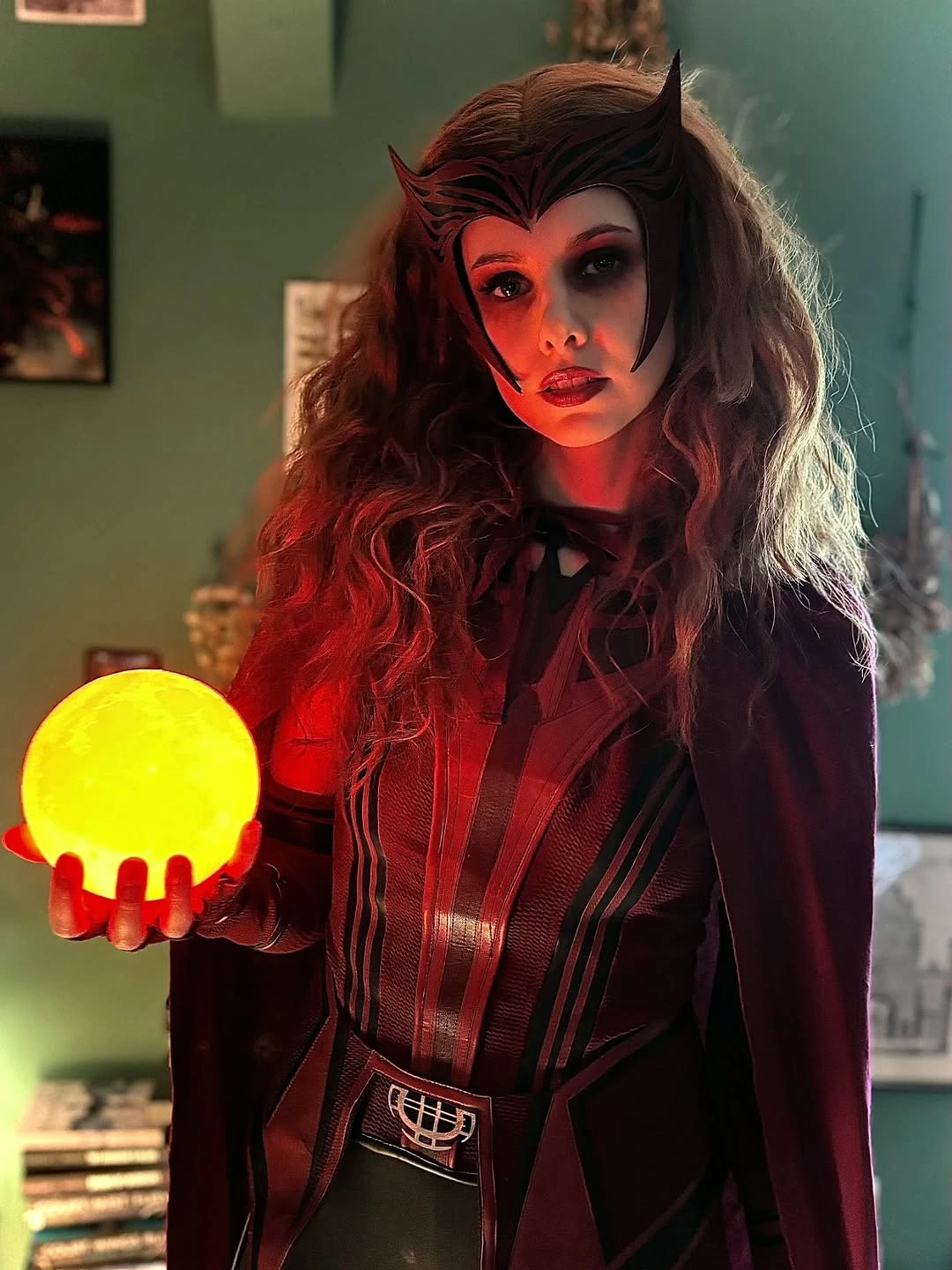 Girl in deep red black costume dark wig and glowing orb prop
