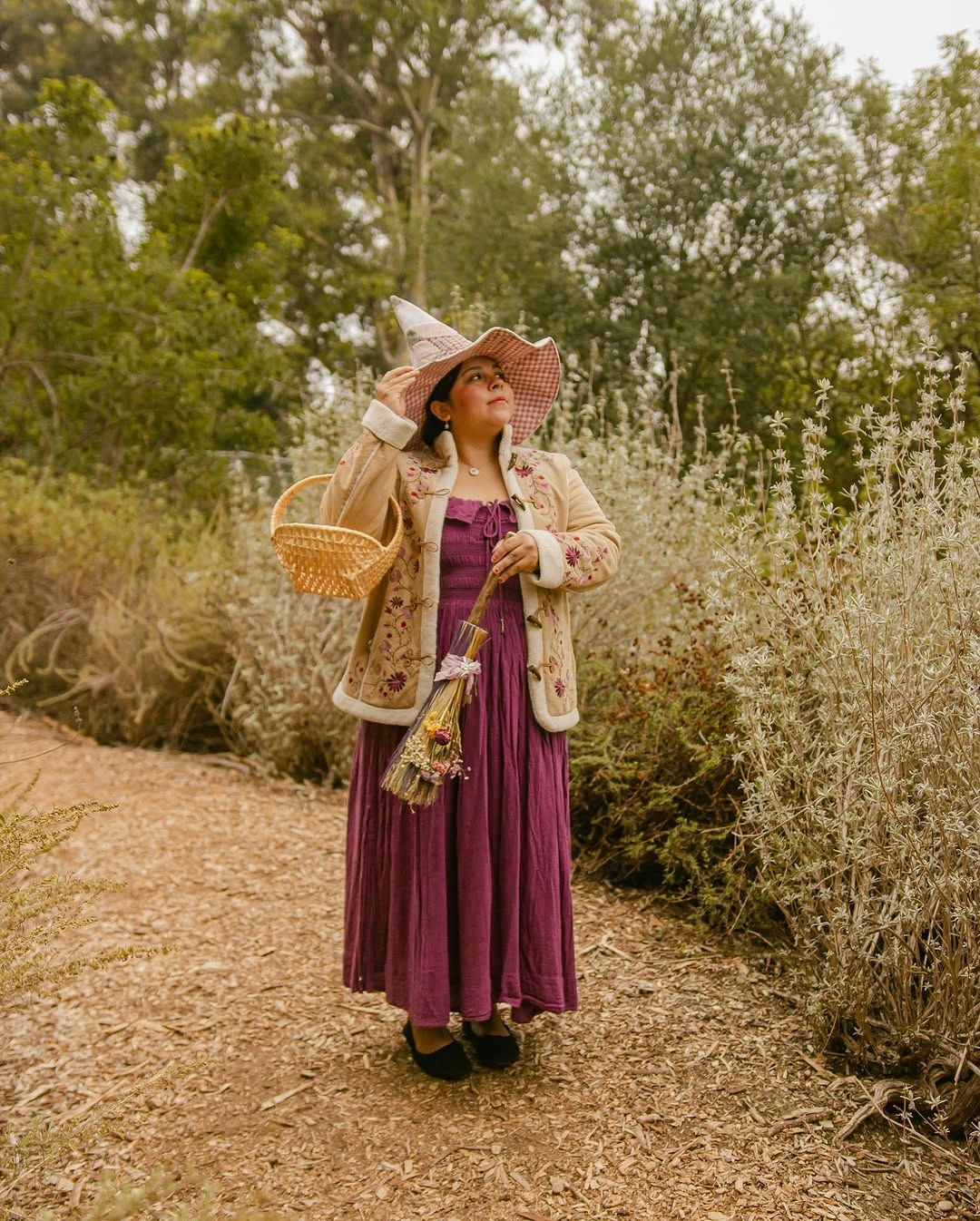 Girl in burgundy tiered dress cream jacket wide brim hat and woven basket
