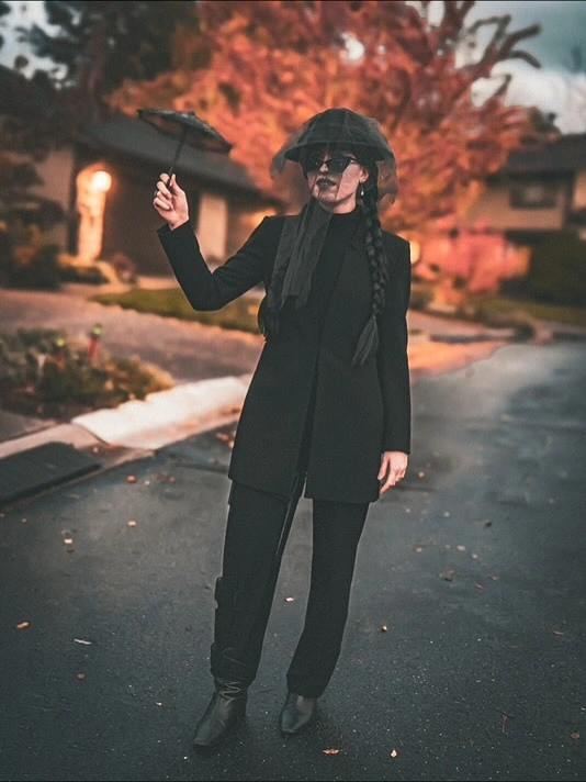 Girl in all black tailored witch outfit pointed hat scarf and sunglasses