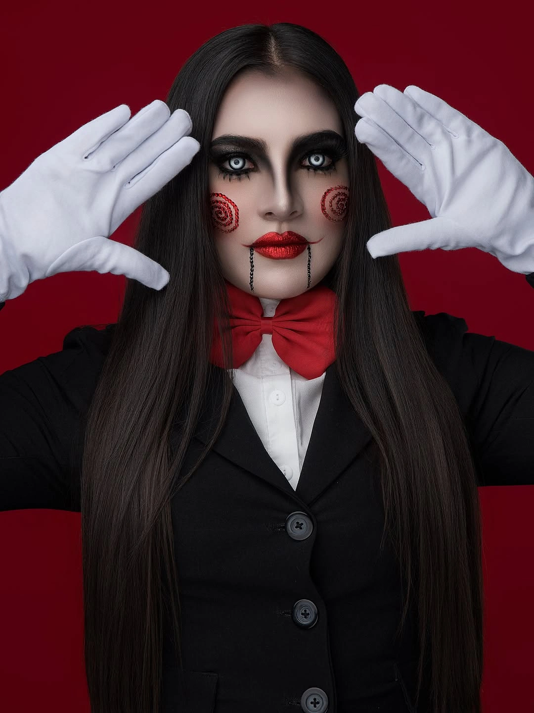 Girl in black suit white collar dark braids and red bow tie