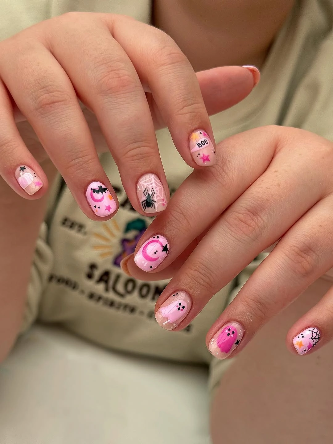 Short pink Halloween nails with cute cartoon faces and small seasonal details