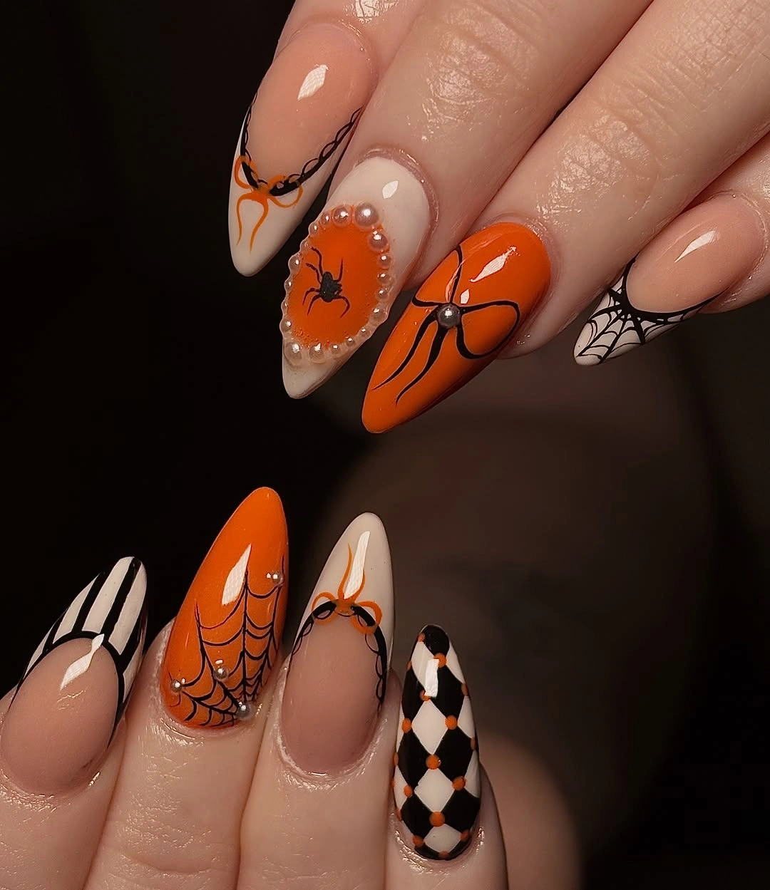 Long orange and black almond Halloween nails with pumpkins and spiderweb details