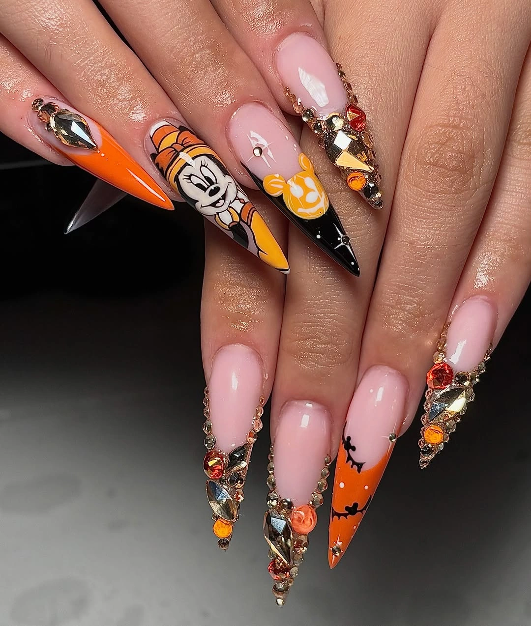 Long orange pink black and white Halloween stiletto nails with jack-o-lanterns charms and gem-like details