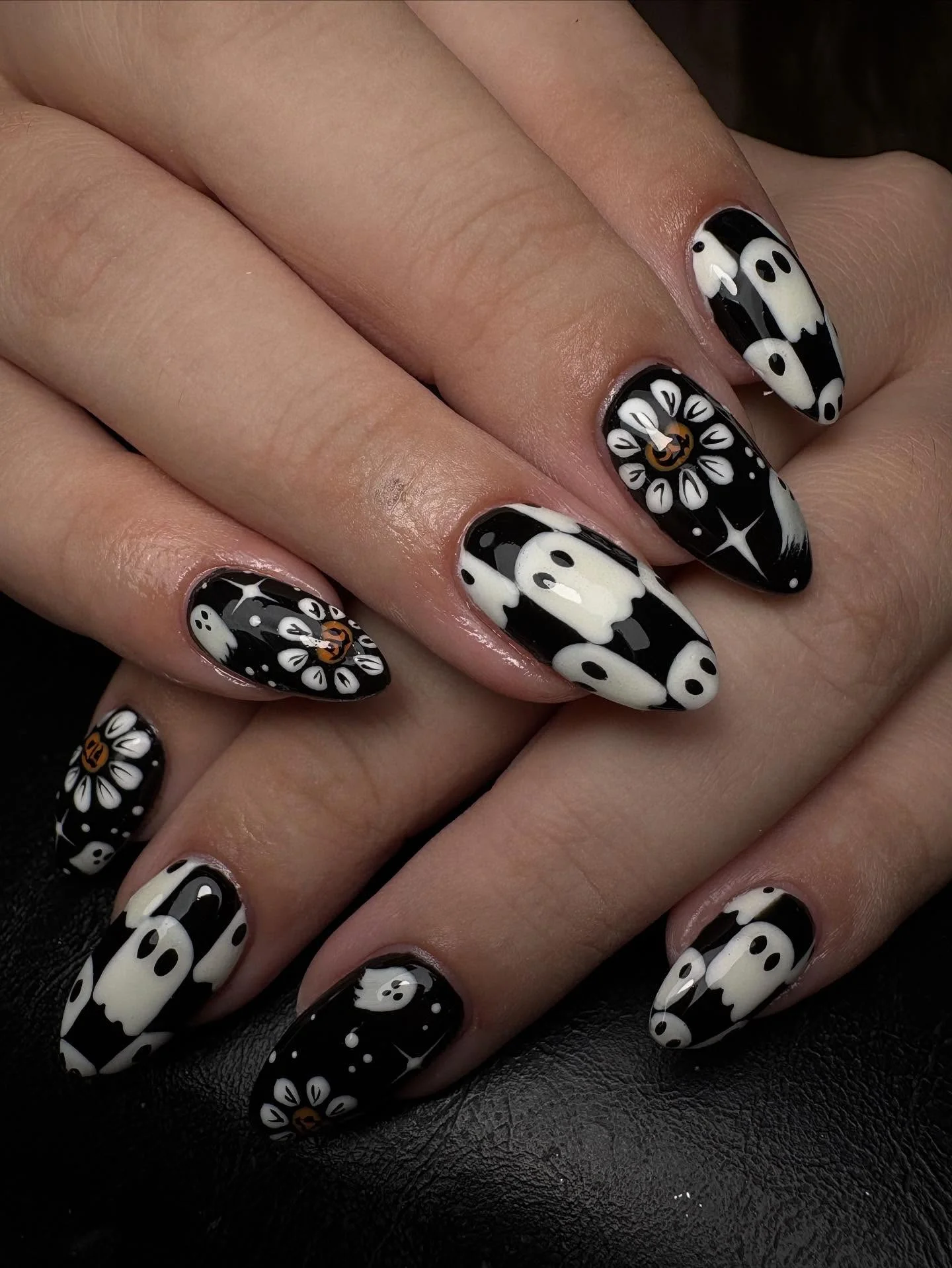 Black and white almond Halloween nails with ghost and flower-like graphic motifs