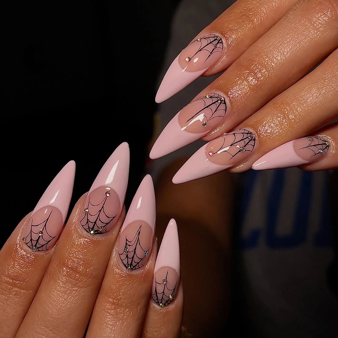 Pink almond Halloween nails with delicate black spiderweb linework