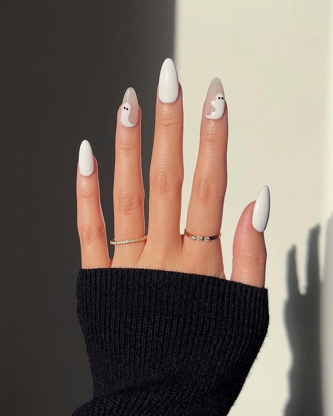 Long pointed white Halloween nails with repeated minimal ghost faces on every nail