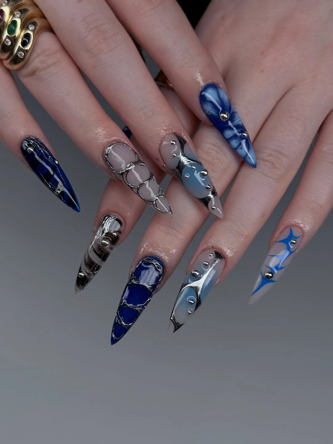 Long blue silver and gray Halloween nails with metallic web-like lines and reflective details