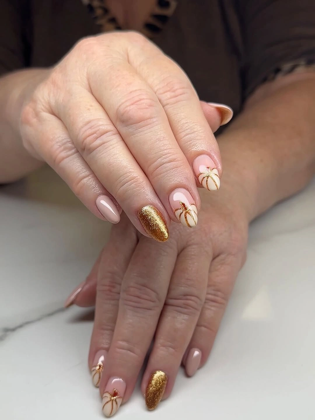 Nude almond nails with fine pumpkin lines flowers and gold glitter