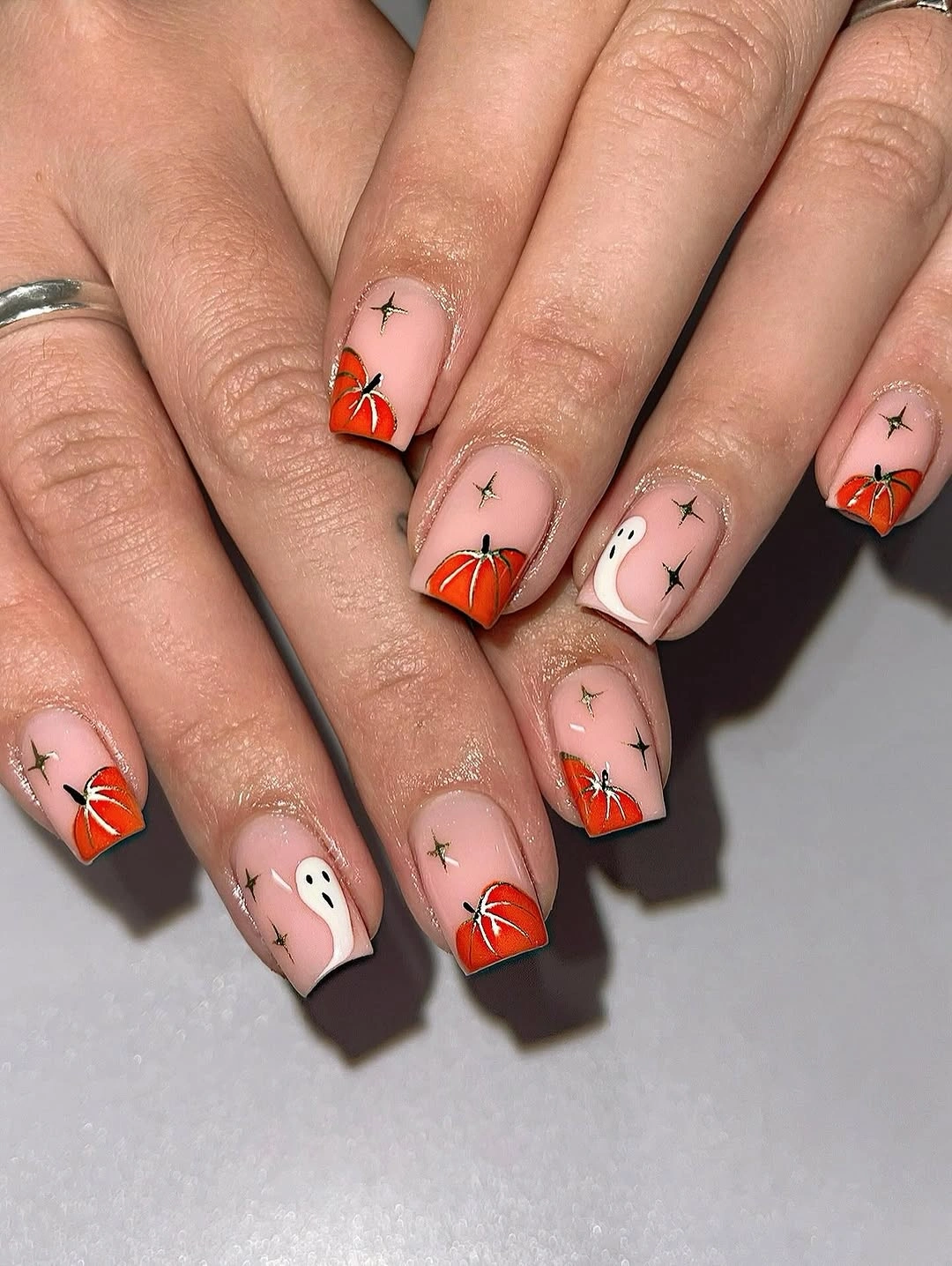 Short nude nails with tiny pumpkins ghost and black stars