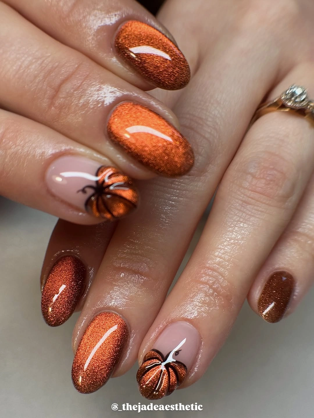 Copper shimmer almond nails with small orange pumpkin designs