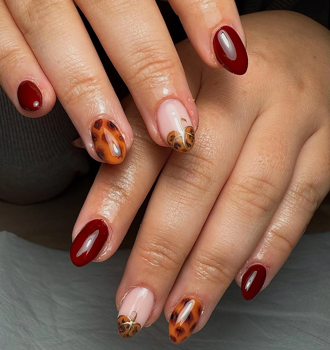 Glossy burgundy almond nails with cream pumpkin accent nails