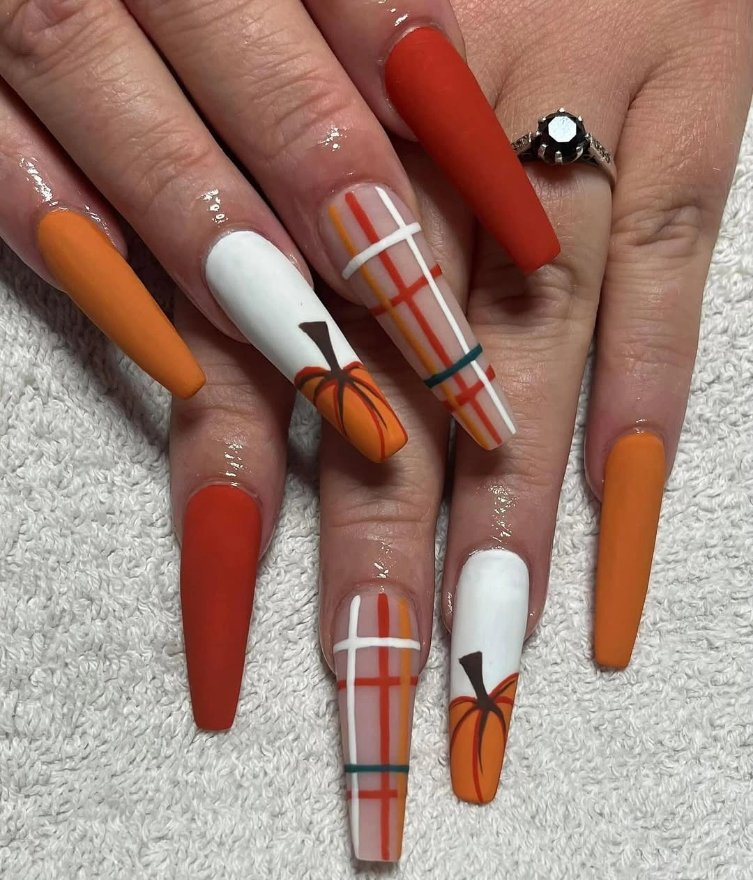 Long matte rust nails with white plaid lines and pumpkin accent