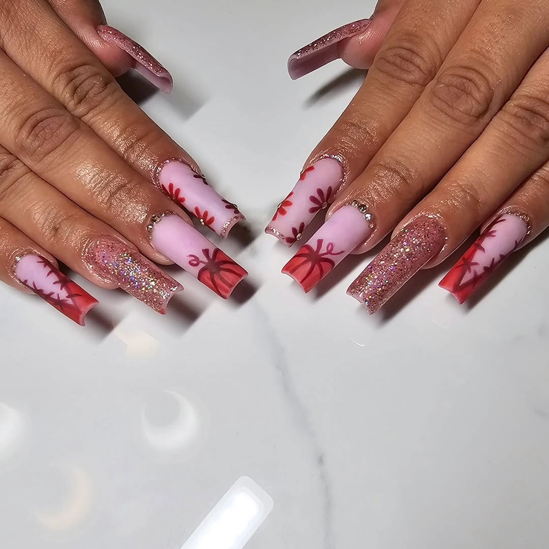 Long pink glitter nails with white skeleton lines and red bow accents