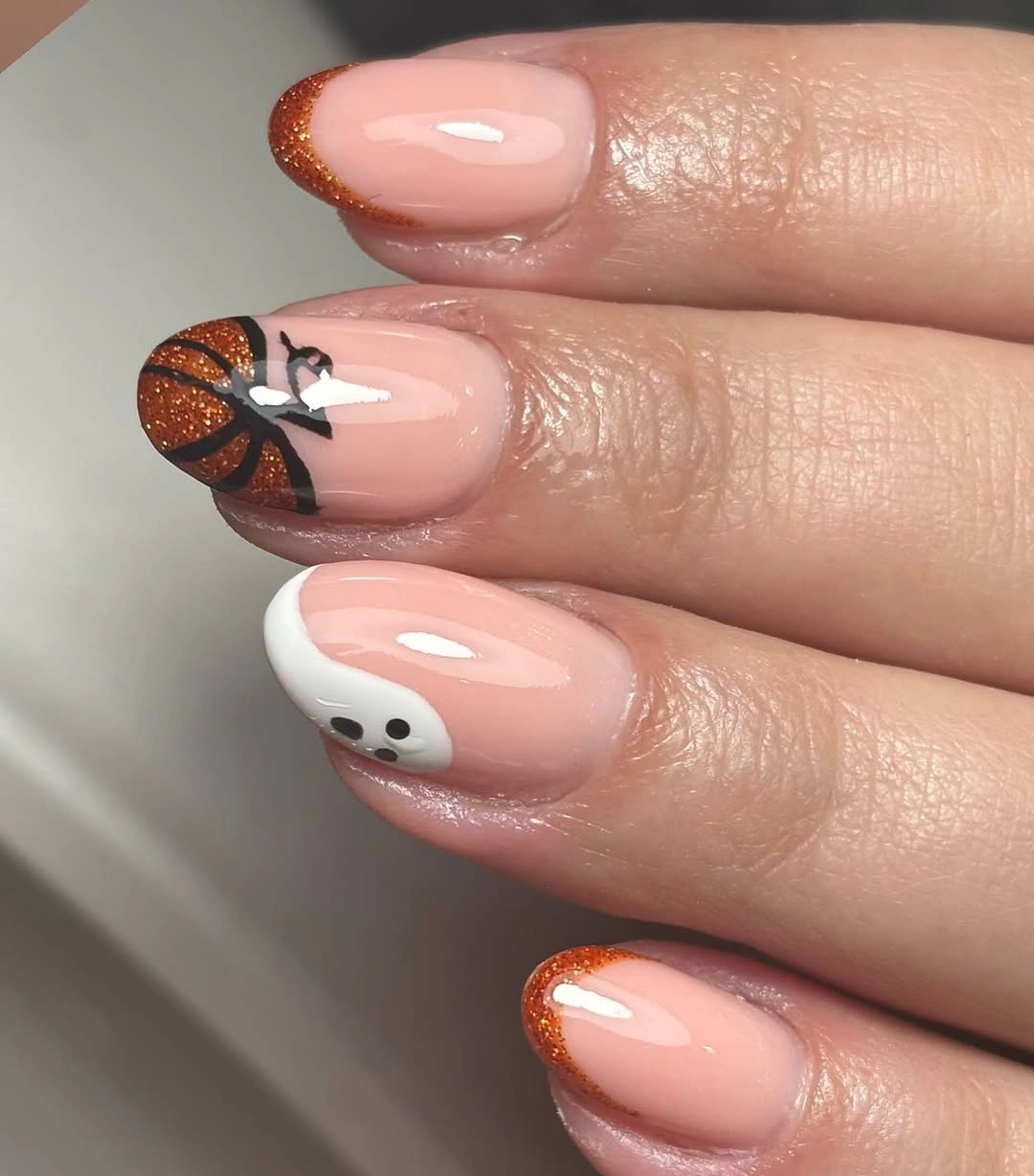 Sheer pink nails with orange French tips bat witch hat and small motifs