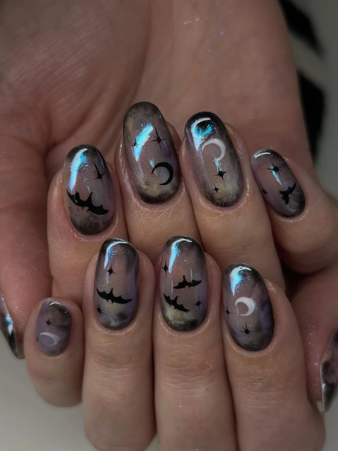 Glossy smoky gray and lilac Halloween nails with black bats and cool blue highlights