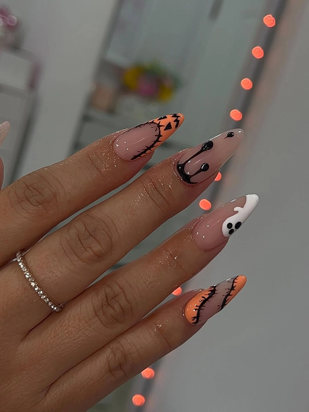 Long orange white and pink Halloween stiletto nails with black spiderwebs and ghosts