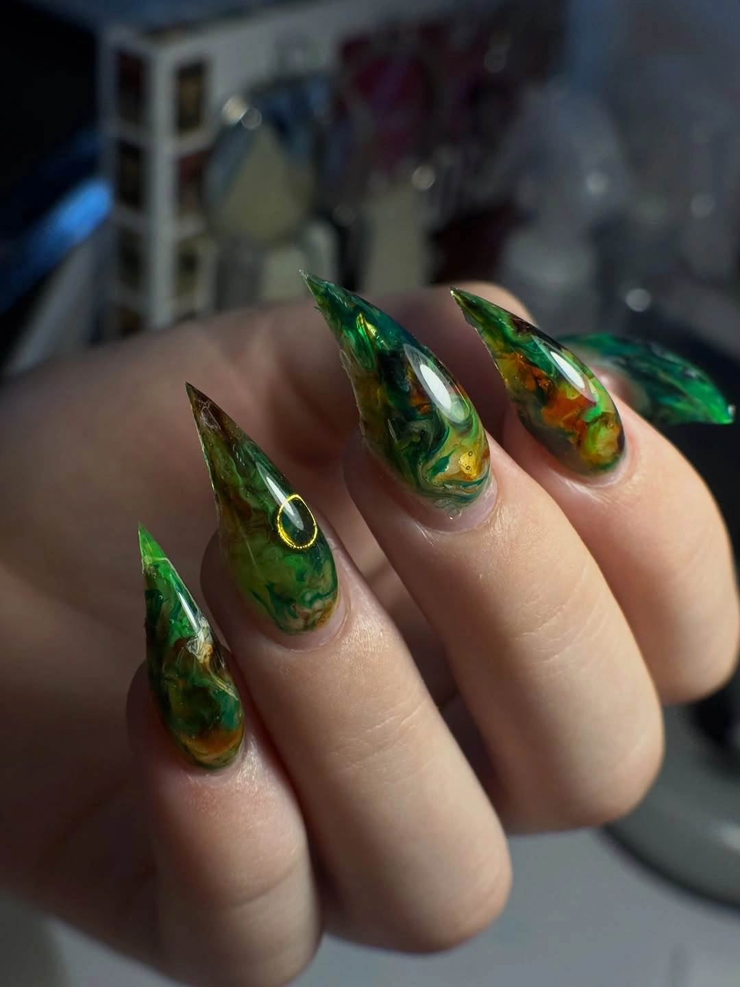 Long pointed green marbled Halloween nails with a dark iridescent finish