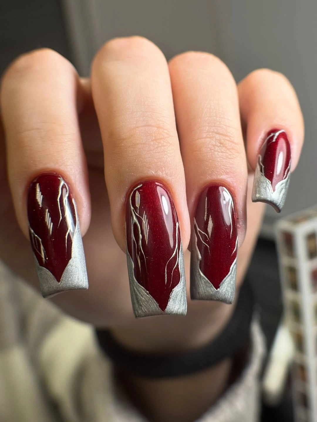 Long glossy burgundy Halloween nails with silver and white pointed edge details