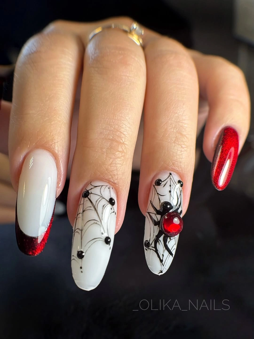 Medium almond pink red and white Halloween nails with spiderweb detail, a black spider, and red jewel