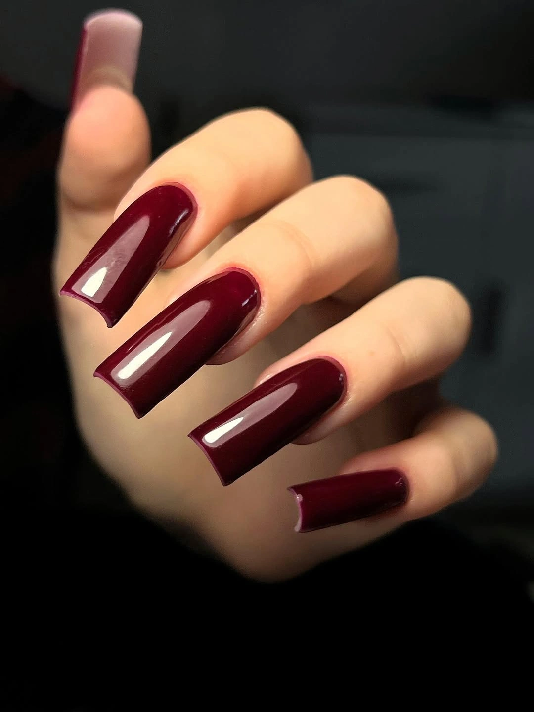 Long deep burgundy square nails in warm reflected light