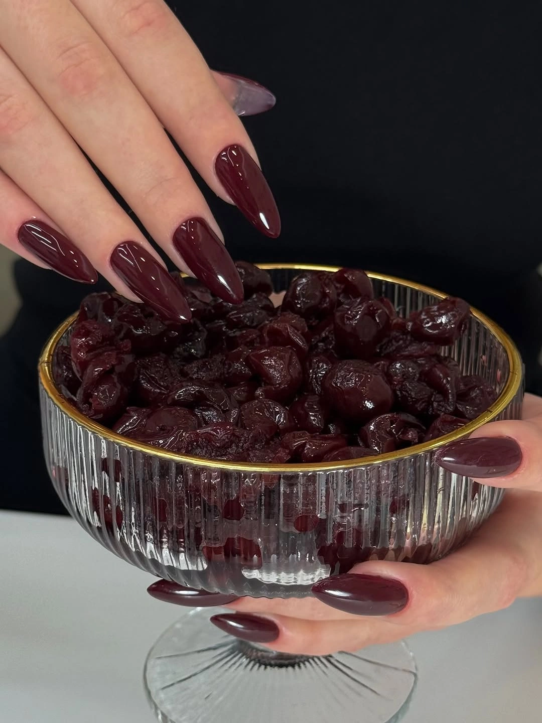 Muted plum maroon almond nails with tonal dark red backdrop