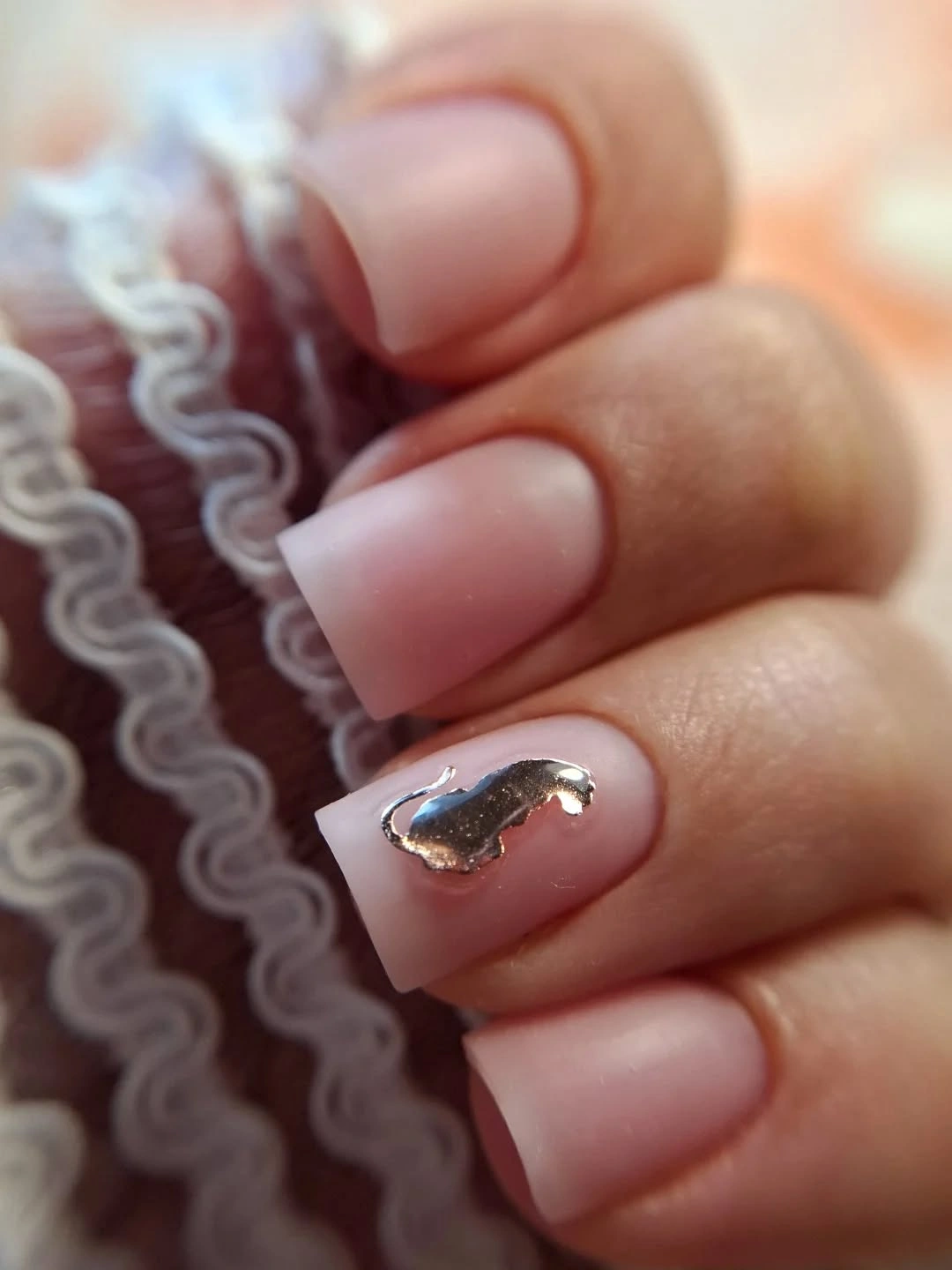 Pale pink square nails with a small reflective curved accent