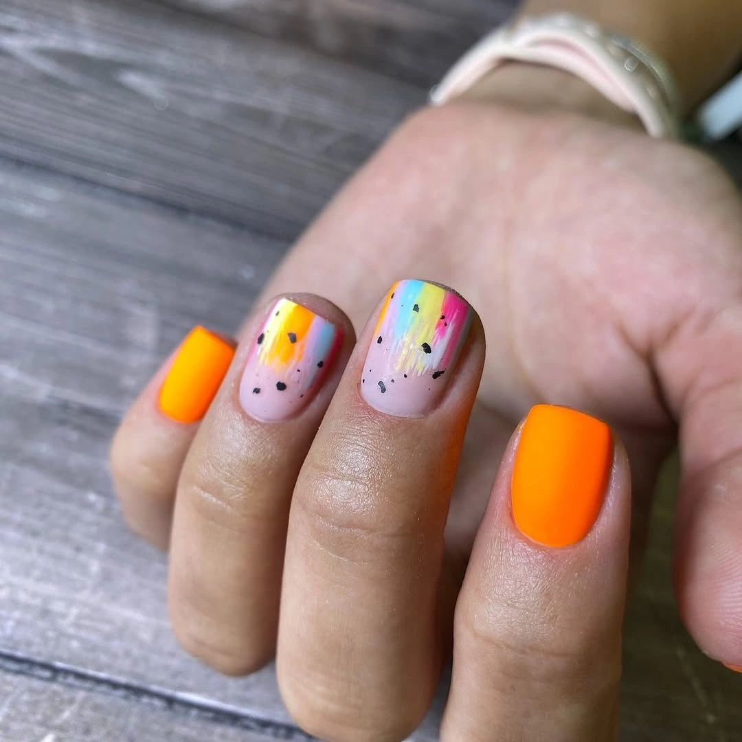 Short neon orange and pale pink nails with colorful sprinkle details
