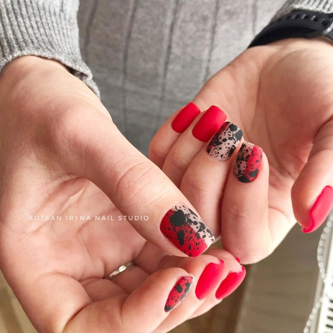 Short red nails with dark patterned accent details