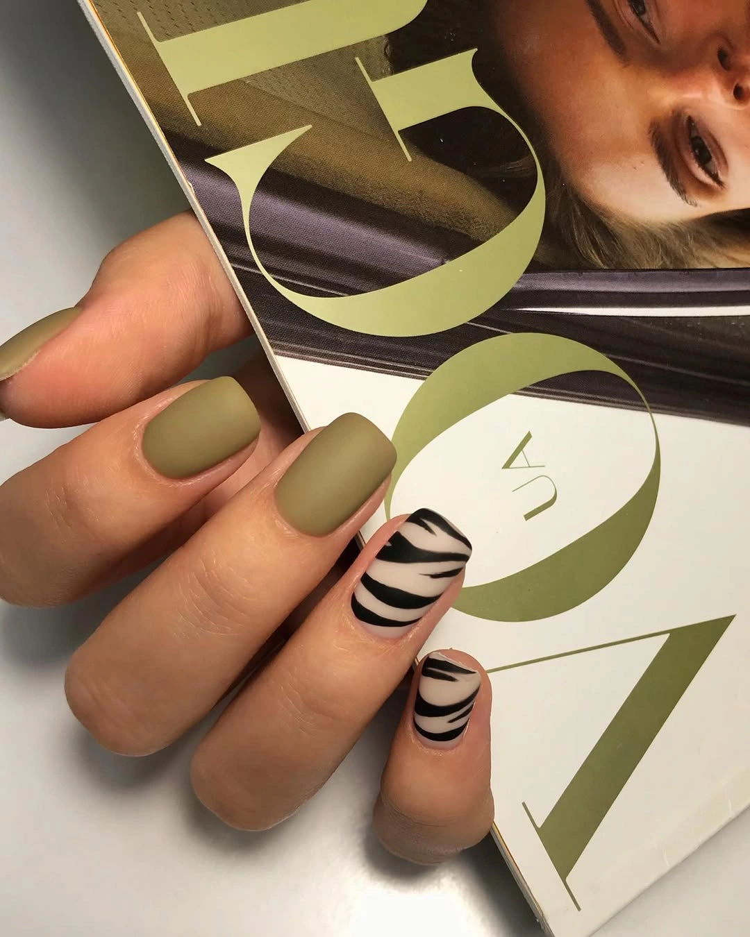 Short olive matte nails with pale zebra stripe accent