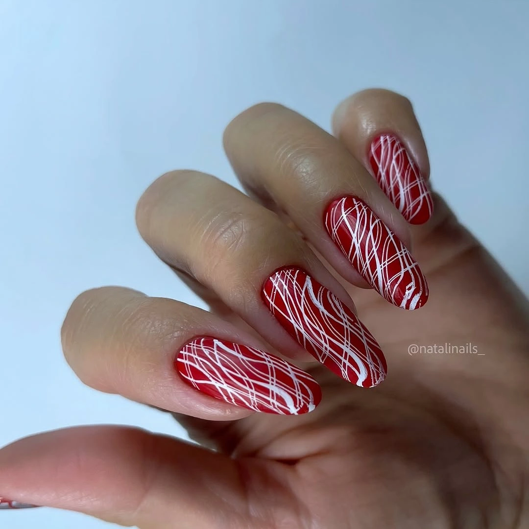 Red almond nails with delicate white thread-like line accents