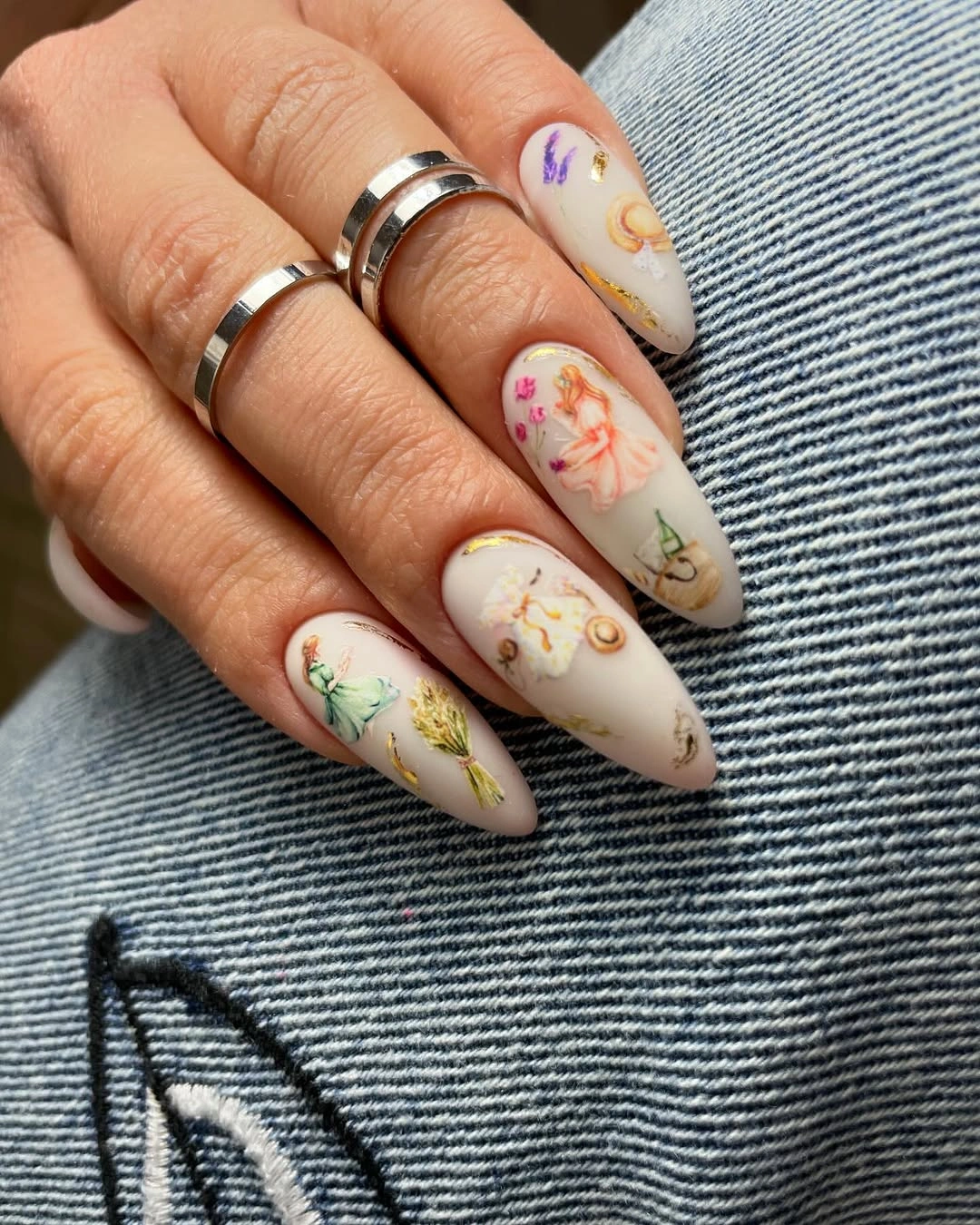 Cream almond nails with tiny colorful floral drawings and gold details