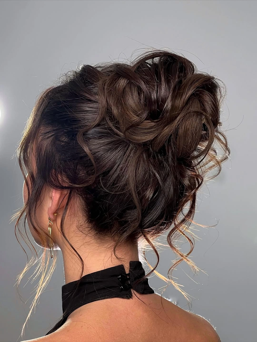 Dark hair gathered into a loose rounded middle-parted updo