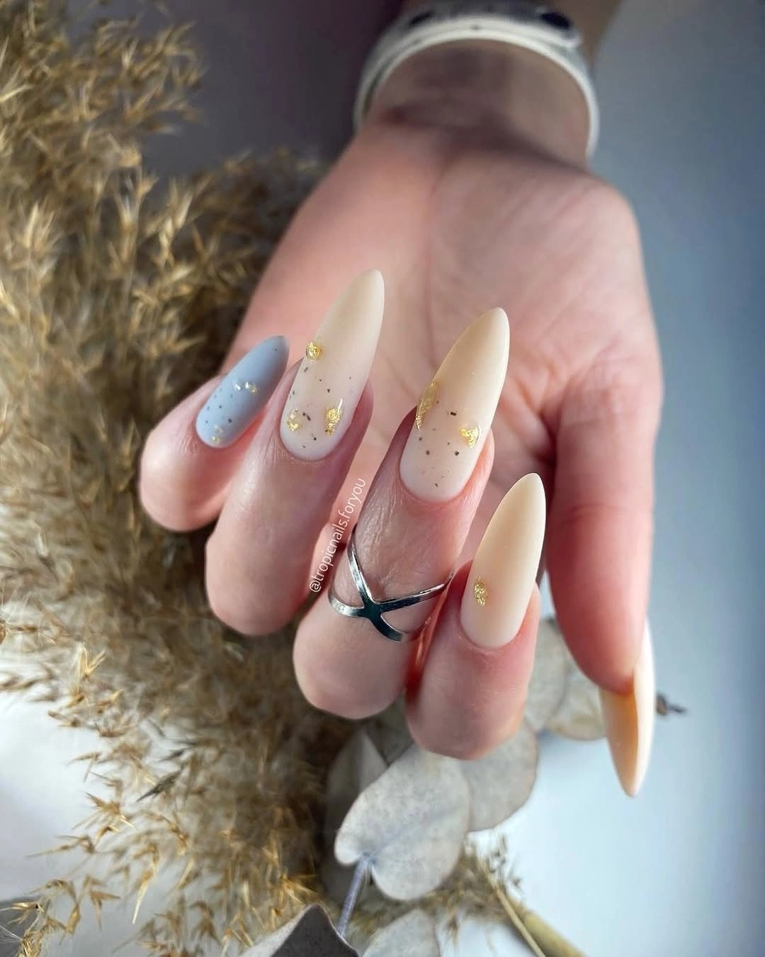 Long almond cream nails with pointed tips and tiny dots