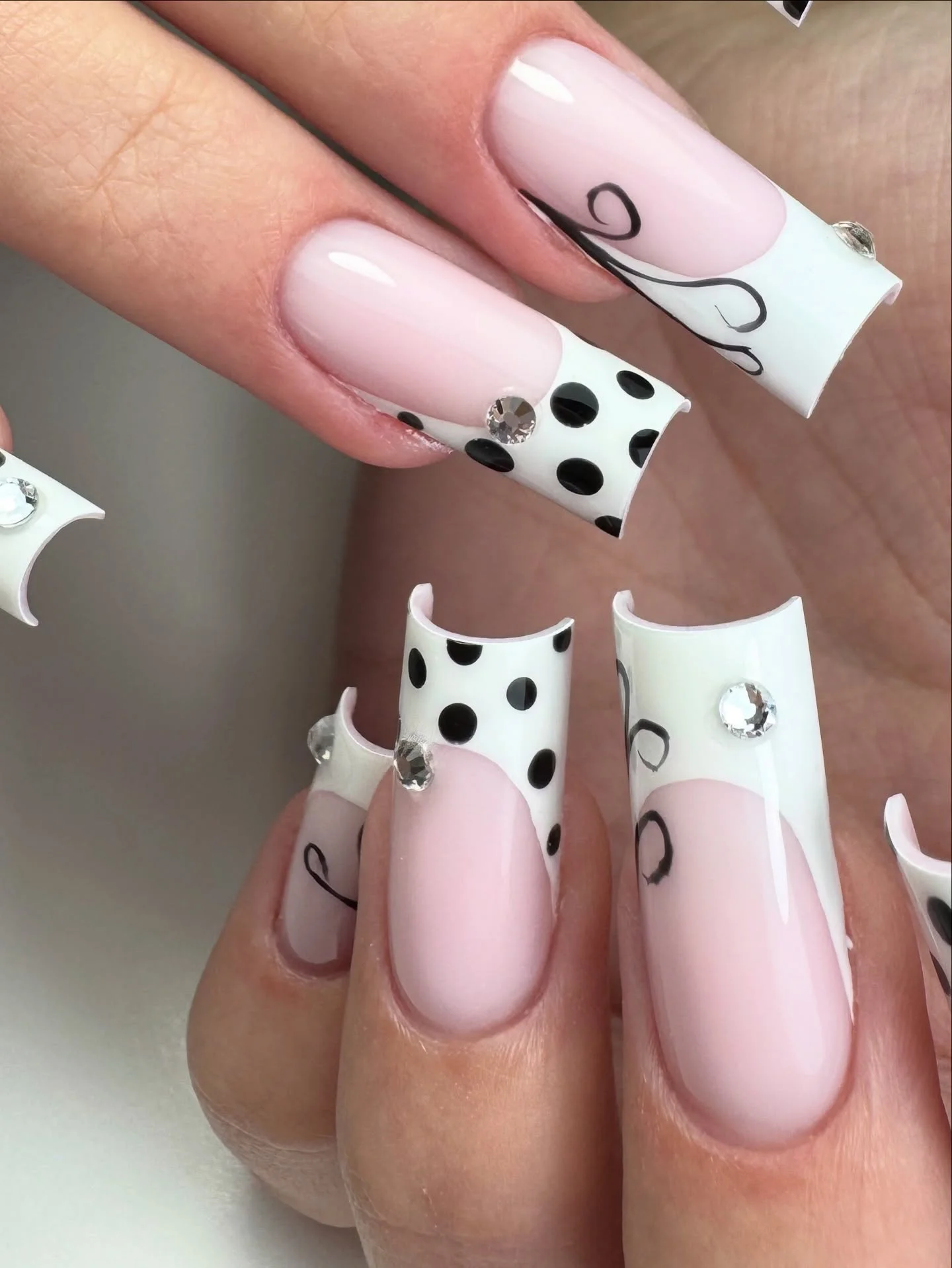 Long pink square nails with white panels black dots and small gems