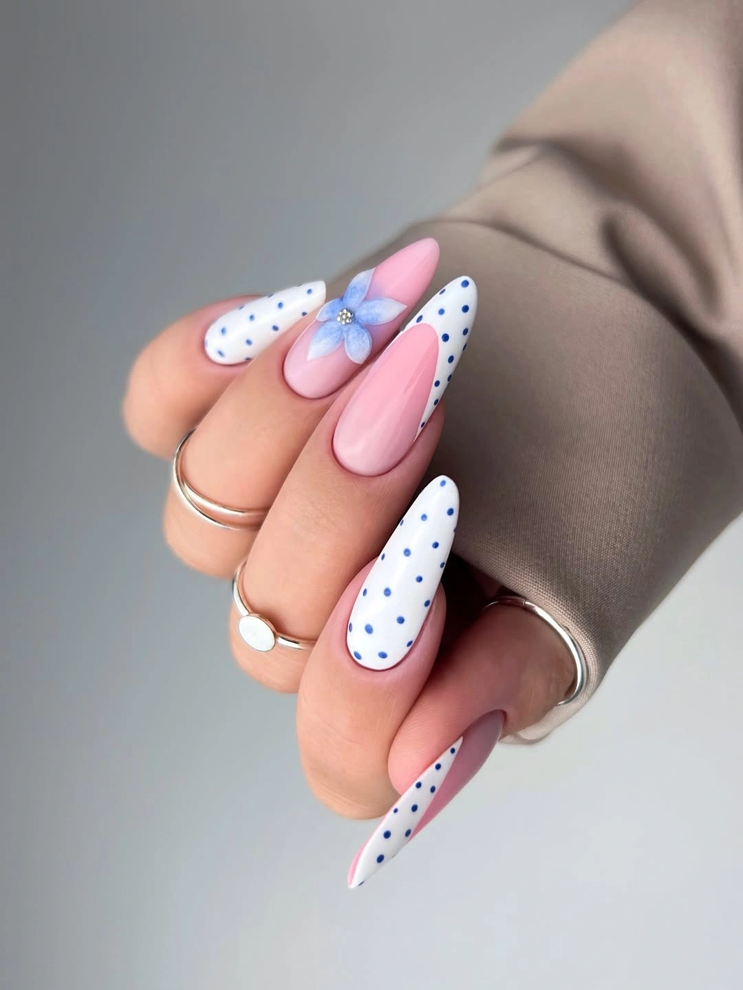 Pink and white pointed nails with blue dots and flower accent