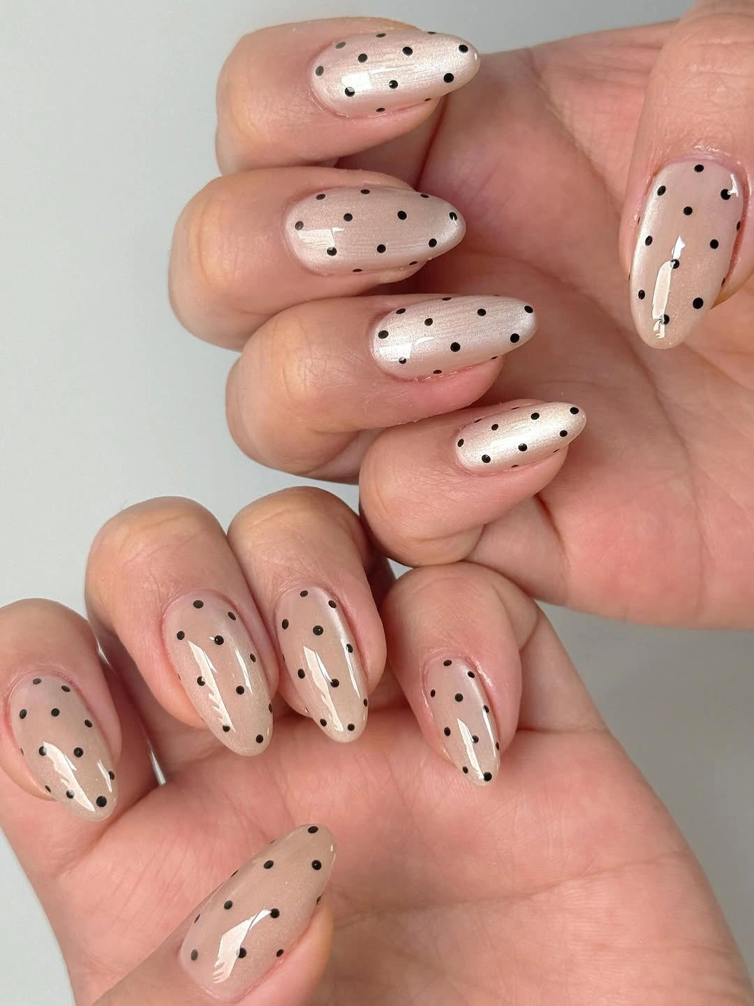 Nude almond nails with tiny black dots and fine dark accents