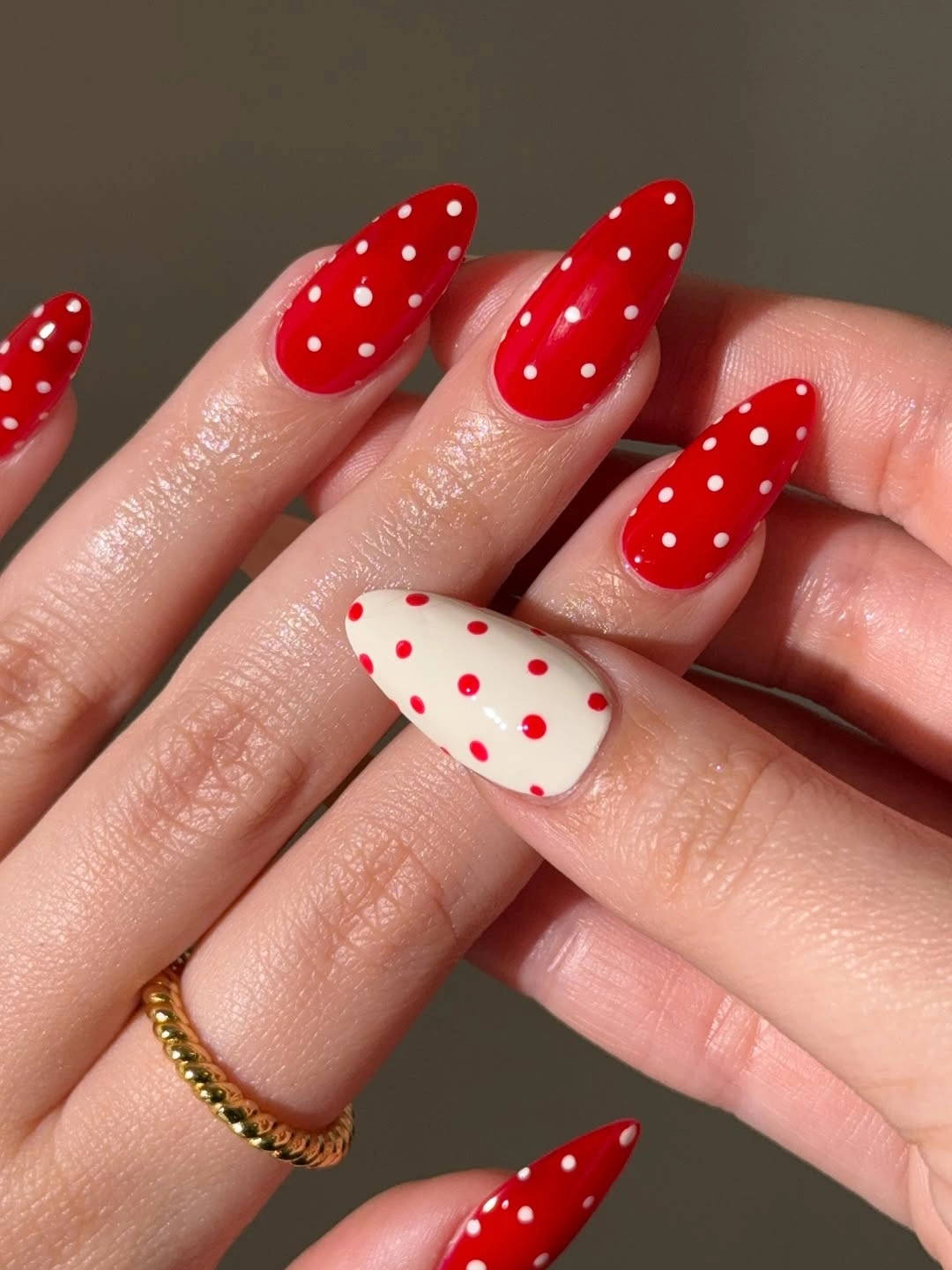 Red almond nails with white dots and pale reverse dot accent
