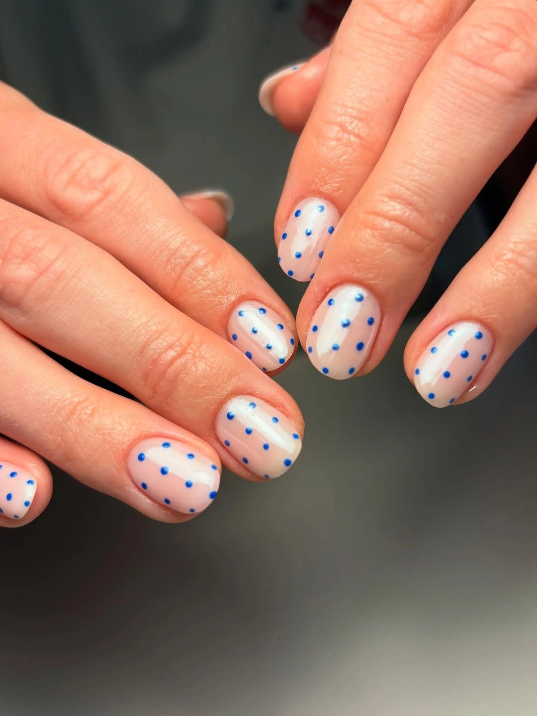 Short nude oval nails with evenly scattered pale blue dots