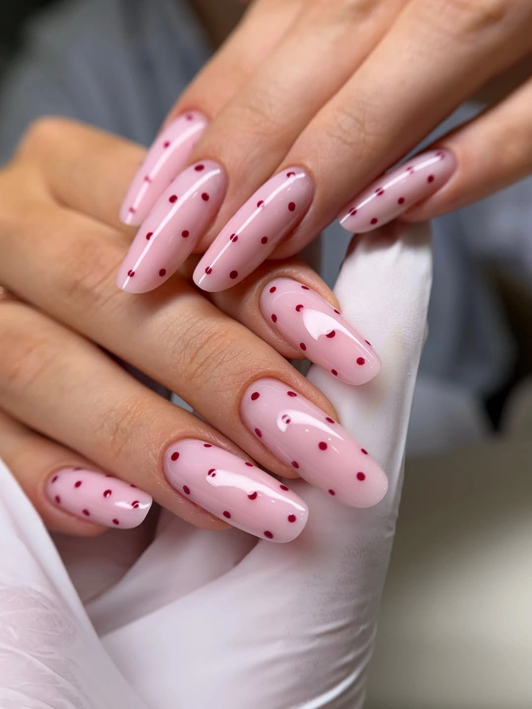 Long pale pink almond nails with small wine red dots