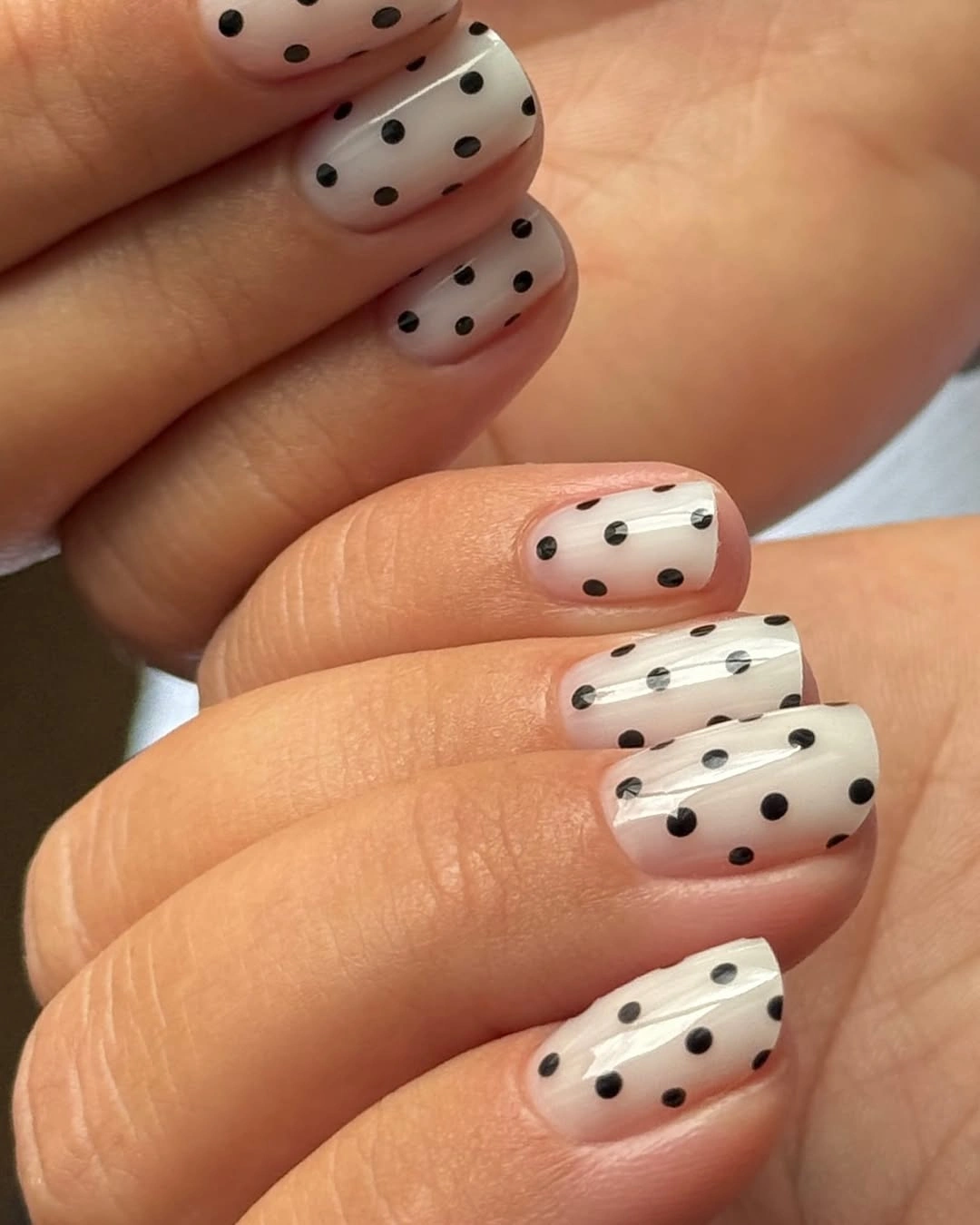 Short white nails with neat crisp black polka dots