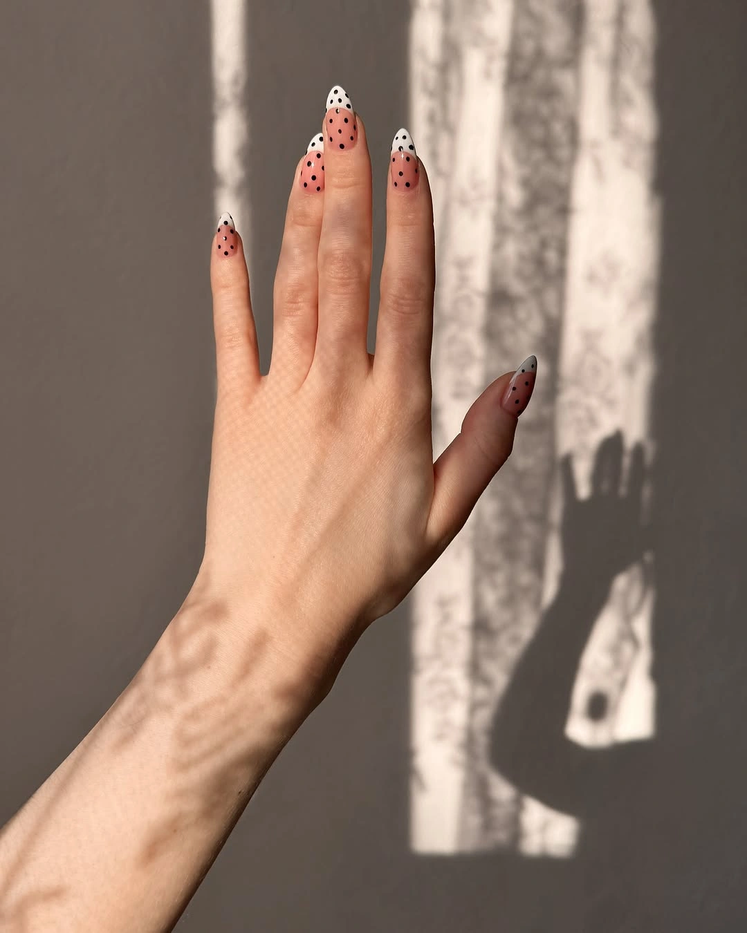 Peach almond nails with white tips and small black dots