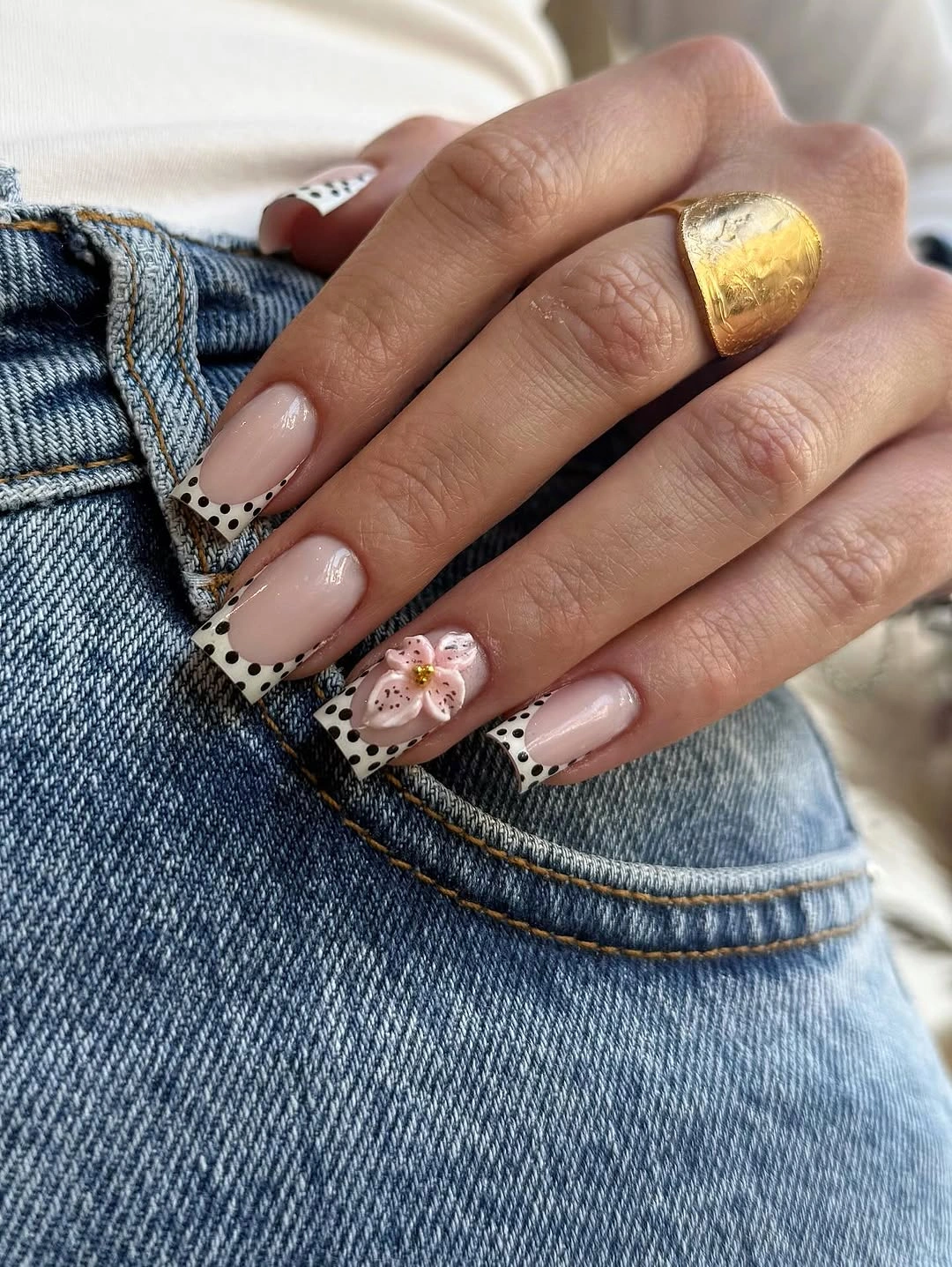 Long nude nails with dark tips black dots and pale flower accent