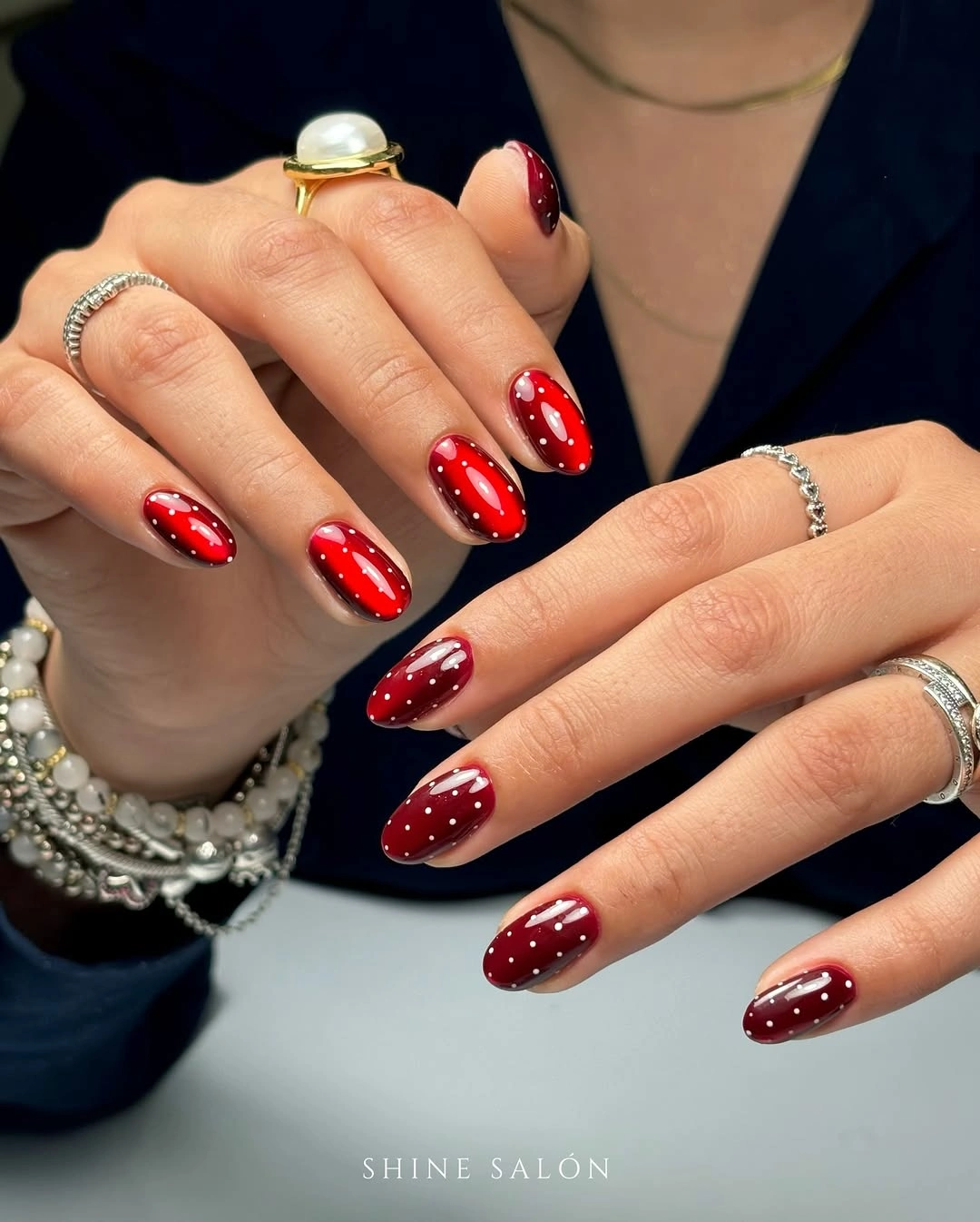 Glossy red almond nails with tiny white dot pattern