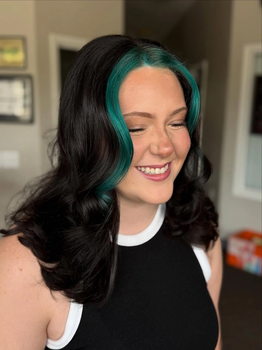 Dark wavy hair with vivid teal face framing streaks