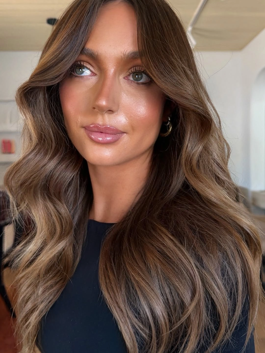 Long medium brown hair with center part and rounded blowout waves